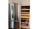 View of a stainless-steel refrigerator beside a pantry with pull-out wooden shelving, offering ample storage at 16341 Maple Rock Ct, Parker, CO 80134