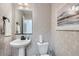 Chic powder room featuring stylish wallpaper, a modern pedestal sink, and sleek fixtures at 4108 Estrella St, Brighton, CO 80601