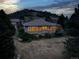 Aerial view of home features lush landscaping, twilight lighting, and scenic hillside backdrop at 6379 Spotted Fawn E Run, Littleton, CO 80125