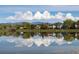 Scenic community view with lake reflecting homes, trees, and cloudscape with mountains in background at 8820 W 80Th Dr, Arvada, CO 80005