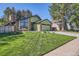 Charming green home featuring brick accents, large windows, manicured lawn and mature trees at 8820 W 80Th Dr, Arvada, CO 80005