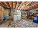 Unfinished basement with exposed beams, laundry area, and shelving at 1395 S Kendall St, Lakewood, CO 80232