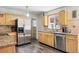 Well-lit kitchen with stainless steel appliances and wood cabinets, granite countertops, and wood-style flooring at 1395 S Kendall St, Lakewood, CO 80232