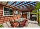 Outdoor seating area with lattice patio cover, brick accents, and table with chairs at 1395 S Kendall St, Lakewood, CO 80232