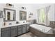 Bathroom with double sinks, cabinets, a soaking tub, and decorative shelving at 13777 W Amherst Way, Lakewood, CO 80228