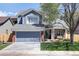 Charming two-story home featuring a gray garage door, blue siding, brick accents, and a well-manicured lawn at 13777 W Amherst Way, Lakewood, CO 80228