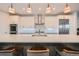 Close-up of modern kitchen with stainless steel appliances, white cabinets, stylish lighting, and bar seating at 427 Milwaukee St, Denver, CO 80206