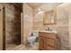 Bathroom with tile flooring and walk-in shower with tiled walls, complemented by a wooden vanity and a matching mirror at 22312 E Plymouth Cir, Aurora, CO 80016