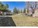 Large backyard featuring green grass, mature trees, and a stone retaining wall with a terraced garden area at 6902 S Jackson Way, Centennial, CO 80122
