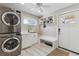Clean and modern laundry room with stacked washer/dryer and a sink, storage, and bench at 6902 S Jackson Way, Centennial, CO 80122
