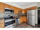 Well-lit kitchen features stainless steel appliances, wood cabinets, and a modern backsplash at 14830 Robins Dr, Denver, CO 80239