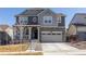 Two story home featuring a covered porch, stone accents, and a two-car garage at 8240 S White Crow St, Aurora, CO 80016