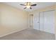 Cozy bedroom features neutral carpet, ceiling fan, and closet with sliding doors at 1065 Cobblestone Dr, Highlands Ranch, CO 80126