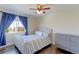 Comfortable bedroom featuring a ceiling fan, dresser, and a window with blue curtains at 4220 Kestrel Dr, Broomfield, CO 80023