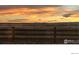A rustic wooden fence is seen at sunset in front of open land at 4220 Kestrel Dr, Broomfield, CO 80023