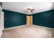 Large bedroom featuring dark teal walls, neutral carpet, and a glimpse into the hallway at 8525 Grandview Ave, Arvada, CO 80002
