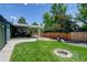 Backyard featuring lush lawn, covered patio with outdoor seating, built in fire pit and a grill at 5986 Dunraven St, Golden, CO 80403