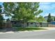 Inviting green home with a mature tree-lined yard, and a cozy front porch with seating at 5986 Dunraven St, Golden, CO 80403