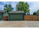 View of the detached garage with a green door and RV parking behind a wood fence at 5986 Dunraven St, Golden, CO 80403