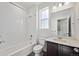 Bright bathroom featuring a tiled shower-tub, toilet, and vanity with a dark cabinet at 1238 Penner Dr, Erie, CO 80026