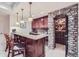 Basement bar area with dark wood bar, granite counters, cabinets, wine storage, and stone archway at 9552 E Silent Hills Pl, Lone Tree, CO 80124