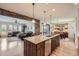 Kitchen with stone accent looking into living and dining rooms, natural wood cabinets and island at 9552 E Silent Hills Pl, Lone Tree, CO 80124