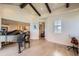 Bright living room with beamed ceilings, hardwood floors, and a grand piano; view to staircase and bookshelves at 9552 E Silent Hills Pl, Lone Tree, CO 80124