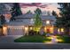 Charming two-story home featuring a brick facade, manicured lawn, and inviting walkway with landscape lighting at dusk at 10849 E Crestridge Cir, Englewood, CO 80111