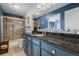 This full bathroom has a black countertop, blue cabinets, and a shower with glass doors at 20290 Doewood Dr, Monument, CO 80132