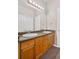 Well-lit bathroom featuring double sinks, wood cabinets, and a large mirror at 8422 S Upham Way # G47, Littleton, CO 80128