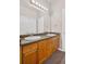 Bathroom featuring dual sinks, wood cabinets, and a large mirror with vanity lighting at 8422 S Upham Way # G47, Littleton, CO 80128