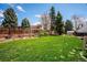 The backyard features a lush green lawn, framed by mature trees and a privacy fence, creating a serene outdoor space at 7863 W Quarto Ave, Littleton, CO 80128