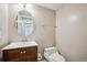 Half bath with wood vanity, sink, and round mirror at 7863 W Quarto Ave, Littleton, CO 80128