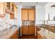 Butler's pantry area with granite countertops, wine fridge, and wooden cabinetry at 27485 E Nova Pl, Aurora, CO 80016