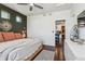 Comfortable bedroom with ceiling fan, dark hardwood floors, accent wall, and view into kitchen at 10560 Waco St, Commerce City, CO 80022