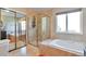 Luxurious bathroom featuring a soaking tub, glass shower, and sliding mirrored closet doors at 1740 Territory Cir, Parker, CO 80138