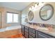 Bright bathroom with double vanity sinks, granite countertop, soaking tub, and a large window at 1740 Territory Cir, Parker, CO 80138