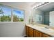 Bathroom featuring a double sink vanity, a large mirror, and a window offering a scenic view at 7868 Downing St, Denver, CO 80229