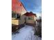 Exterior view of the home's side, featuring brick accents, a red roof, and a door with snowy surroundings at 2060 S Washington St, Denver, CO 80210