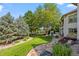 Beautiful backyard featuring mature trees, manicured lawn, and a stone-paved pathway at 2378 Plumb Pl, Erie, CO 80516