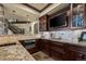Elegant bar area featuring granite countertops, dark wood cabinetry, and a mounted television at 2378 Plumb Pl, Erie, CO 80516