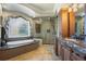 Luxurious bathroom with soaking tub, glass-enclosed shower, and marble countertops on custom cabinetry at 2378 Plumb Pl, Erie, CO 80516