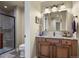 Well-lit bathroom featuring a glass-enclosed shower, tiled floor, and granite vanity with modern lighting at 2378 Plumb Pl, Erie, CO 80516