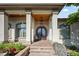 Covered front entrance featuring a beautiful wooden door, elegant columns, and manicured landscaping at 2378 Plumb Pl, Erie, CO 80516