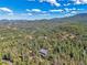 Aerial view showcases the mountain home nestled in a lush forest setting with a view of the mountains at 6979 Weasel Way, Evergreen, CO 80439