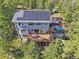 Aerial view displays home with a deck, a hot tub, and solar panels in a serene forest setting at 6979 Weasel Way, Evergreen, CO 80439