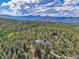 Aerial shot shows mountain home surrounded by lush forests and stunning mountain scenery at 6979 Weasel Way, Evergreen, CO 80439