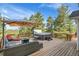 Outdoor deck with hot tub, lounge furniture, fire table, umbrella, and beautiful treed mountain views at 6979 Weasel Way, Evergreen, CO 80439