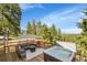 Outdoor deck with hot tub, patio furniture, and views of the surrounding forest at 6979 Weasel Way, Evergreen, CO 80439