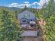 View of home with an expansive deck with a hot tub and outdoor seating, surrounded by trees at 6979 Weasel Way, Evergreen, CO 80439